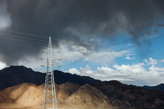 Electricity Pylons Against Stormy Mountain Backdrop