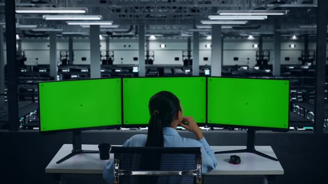 Back View Of Asian Woman Thinking About Something While Working With Mock Up Multiple Computer Monitor In Data Center