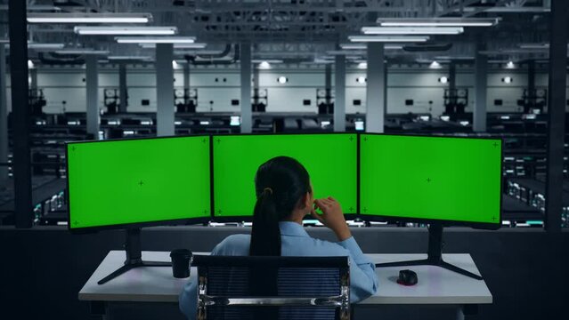 Back View Of Asian Woman Thinking About Something Then Raising Her Index Finger While Working With Mock Up Multiple Computer Monitor In Data Center