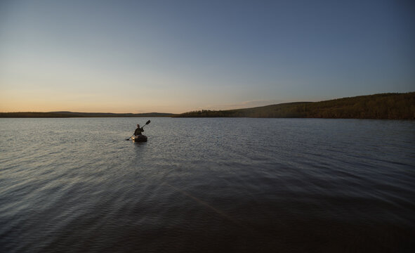 Woman paddling a packraft on a calm body of water