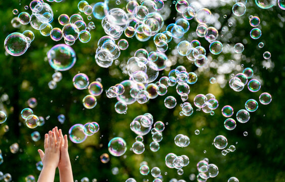 children's hands catching soap bubbles