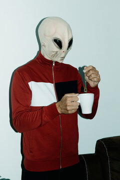 man wearing an alien mask preparing a cup of tea