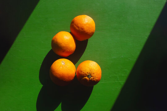 Juicy oranges ona green wooden table with direct sunlight