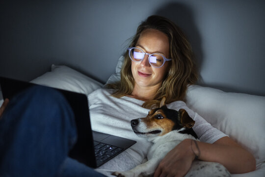 Young Woman and Her Dog Using Laptop in Bed 
