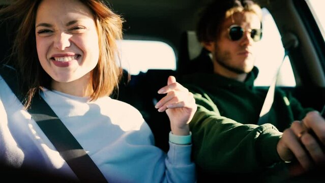 loving couple is driving in a car on a sunny day and having fun, traveling by car.