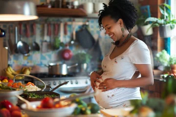 Fotobehang A joyful expectant mother, adorned with colorful beads, lovingly caresses her belly in a sunny, plant-filled kitchen, surrounded by fresh vegetables and home-cooked meals. © Maria