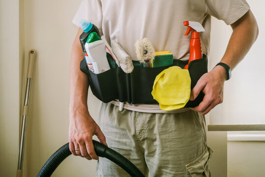 An unrecognizable man poses with brushes and home cleaning products