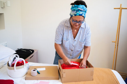 mature Woman Customizing Gift Package with Handwritten Card 