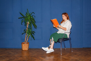A disabled woman with a plus size and a prosthetic leg reads a book