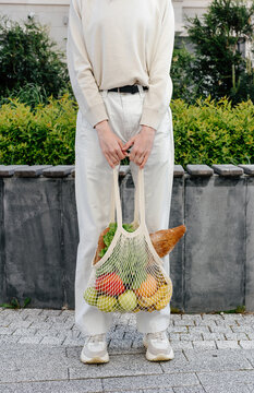 Crop woman with mesh bag of fresh groceries, zero waste 