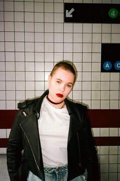 Portrait of millennial female on tile wall background, direct flash