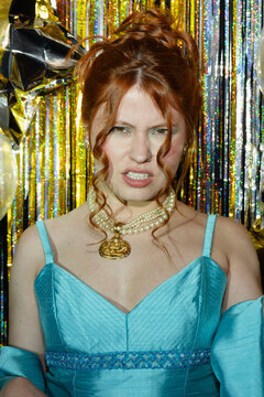 Girl in blue dress having fun and posing among golden confetti