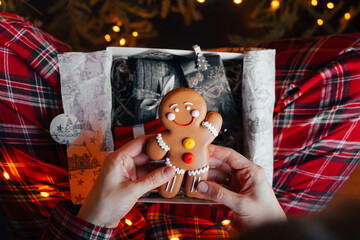 hands with present gift box, gingerbread man by twinkling xmas tree