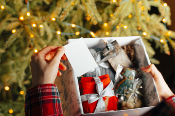 Woman opening Christmas present gift box near xmas tree at home