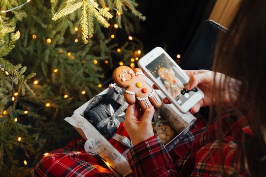 Woman opening Christmas present gift box near the xmas tree at home