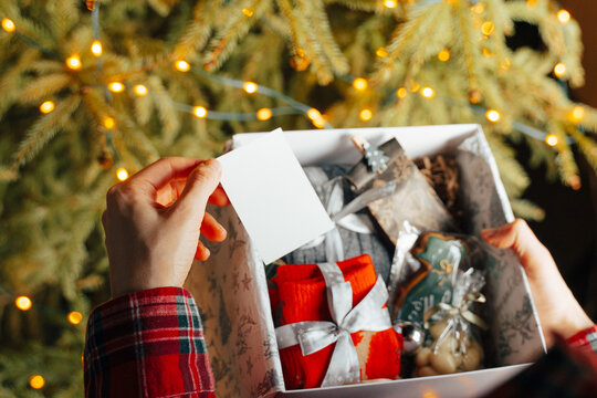 Woman opening Christmas present gift box near xmas tree at home