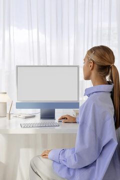 a woman works at a computer with a white screen in a modern office