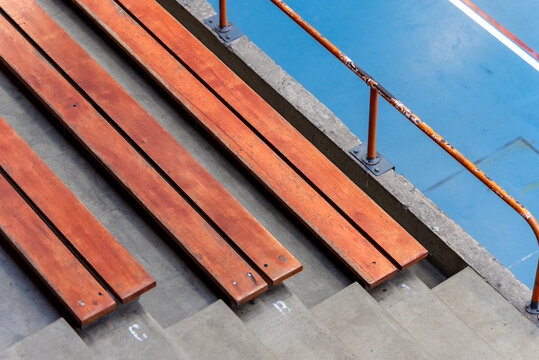 Wooden indoor bleachers above a blue sport court