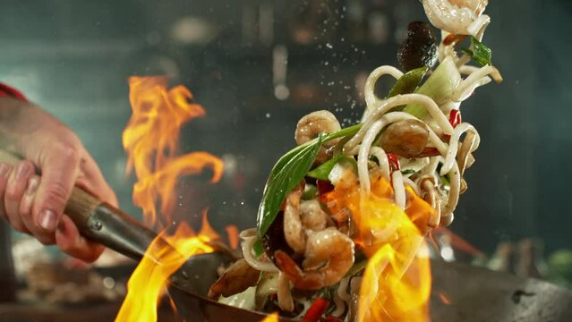 Super slow motion of flying asian wok noodles with prans and vegetable. Filmed on high speed cinema camera, 1000 fps. Speed ramp effect.