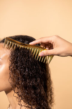 A woman combs her wet curly hair with a comb.