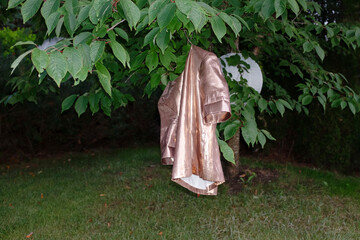 Rosegold / copper t-shirt hanging on a tree in a garden 
