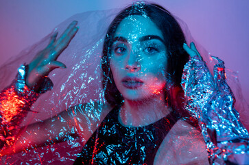 High Fashion model woman in colorful bright neon blue and purple lights posing in studio. Portrait...