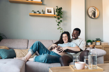 Diverse pregnant couple In Love Cuddling On The Sofa