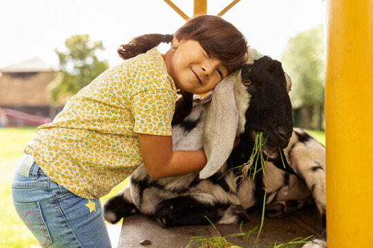 cute little girl hugging a goat