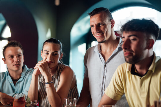 Group of friends chatting at a cafe/bar and having cocktails