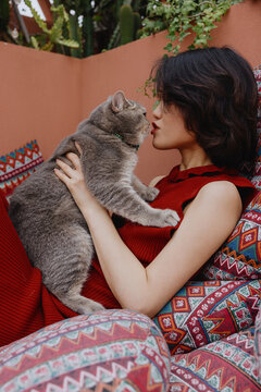 young Asian woman kissing a fluffy cat outdoor