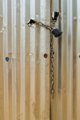 Close-up photography of a iron chain and a padlock  securing a improvised zinc door, in a construction site near the town of Villa de Leyva, in central Colombia.