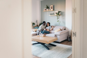 Diverse pregnant couple In Love Cuddling On The Sofa