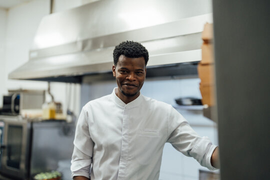 Happy black man in uniform standing in kitchen
