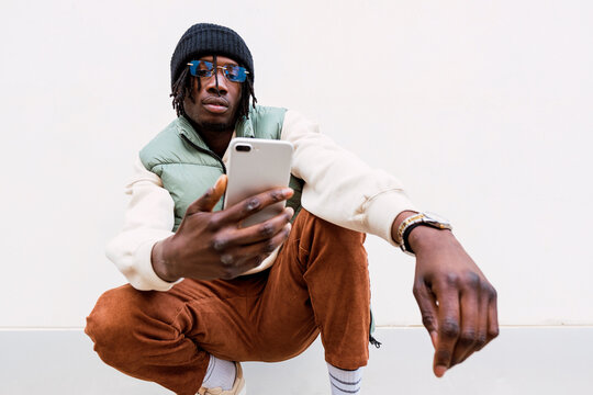 Stylish black man browsing smartphone in city