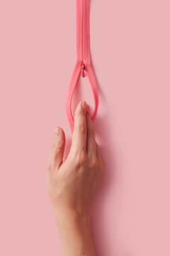 Woman putting fingers inside space of opened pink zipper