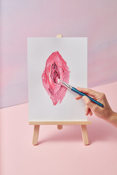 Close up of artist hand painting on canvas female anatomy of vulva
