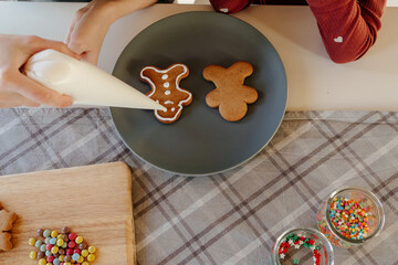 Mother and daughter painting gingerbread man with icing