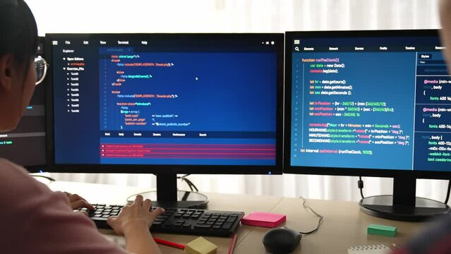 Slow motion back end software developer engineer for computer programming working together on debugging writing computing code, solving complex algorithms display on monitor in office. Burgeoning
