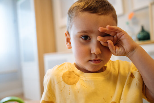 Tired little boy rubbing eyes