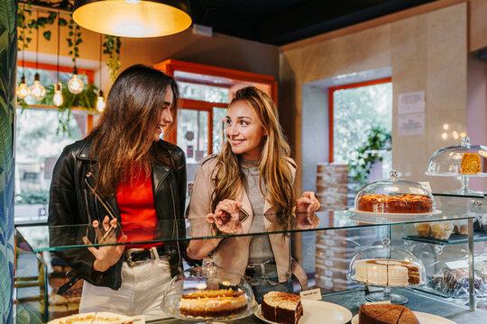 good friends choosing a slice of cake from the cafeteria counter