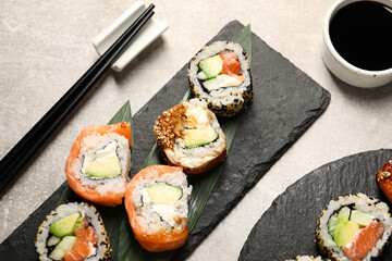 Delicious sushi rolls, soy sauce and chopsticks on light grey table, above view