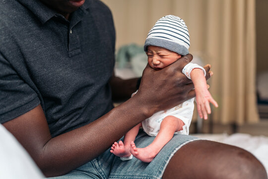 Newborn baby being held by dad after birth