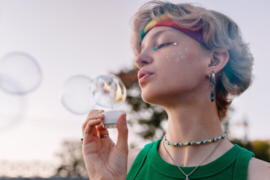 Sensual lgbtq woman blowing bubbles in nature