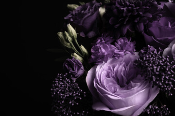 Bouquet with violet flowers on black background, closeup. Funeral attributes