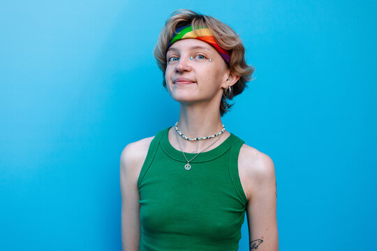 Stylish queer woman in colorful outfit looking at camera in studio