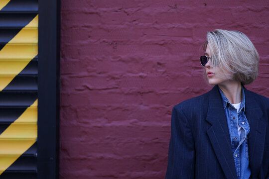 Woman standing in front of purple brick wall and caution stripes