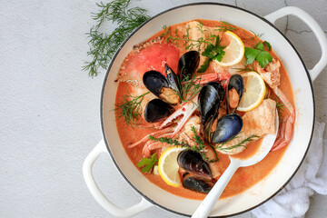 A classic French bouillabaisse in a large pot, set against a white background