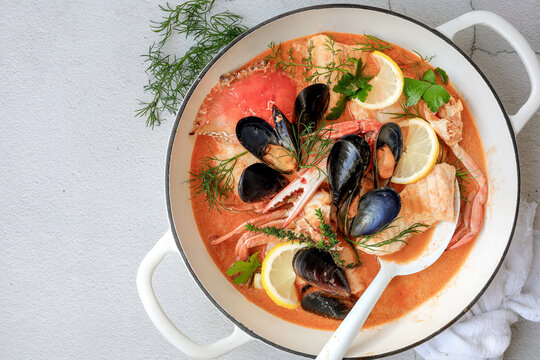 A classic French bouillabaisse in a large pot, set against a white background