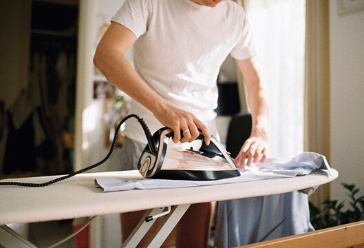 A man ironing his shirts and home