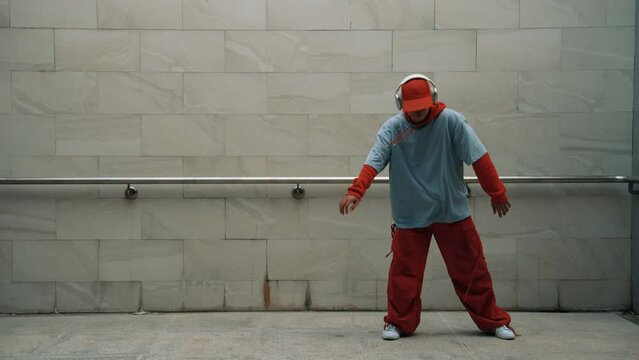 Handsome choreographer practice street dance in gray background. Young attractive b boy dancer perform while wearing stylish cloth. Feeling of lively step. Copy space. Outdoor sport 2024. Sprightly.